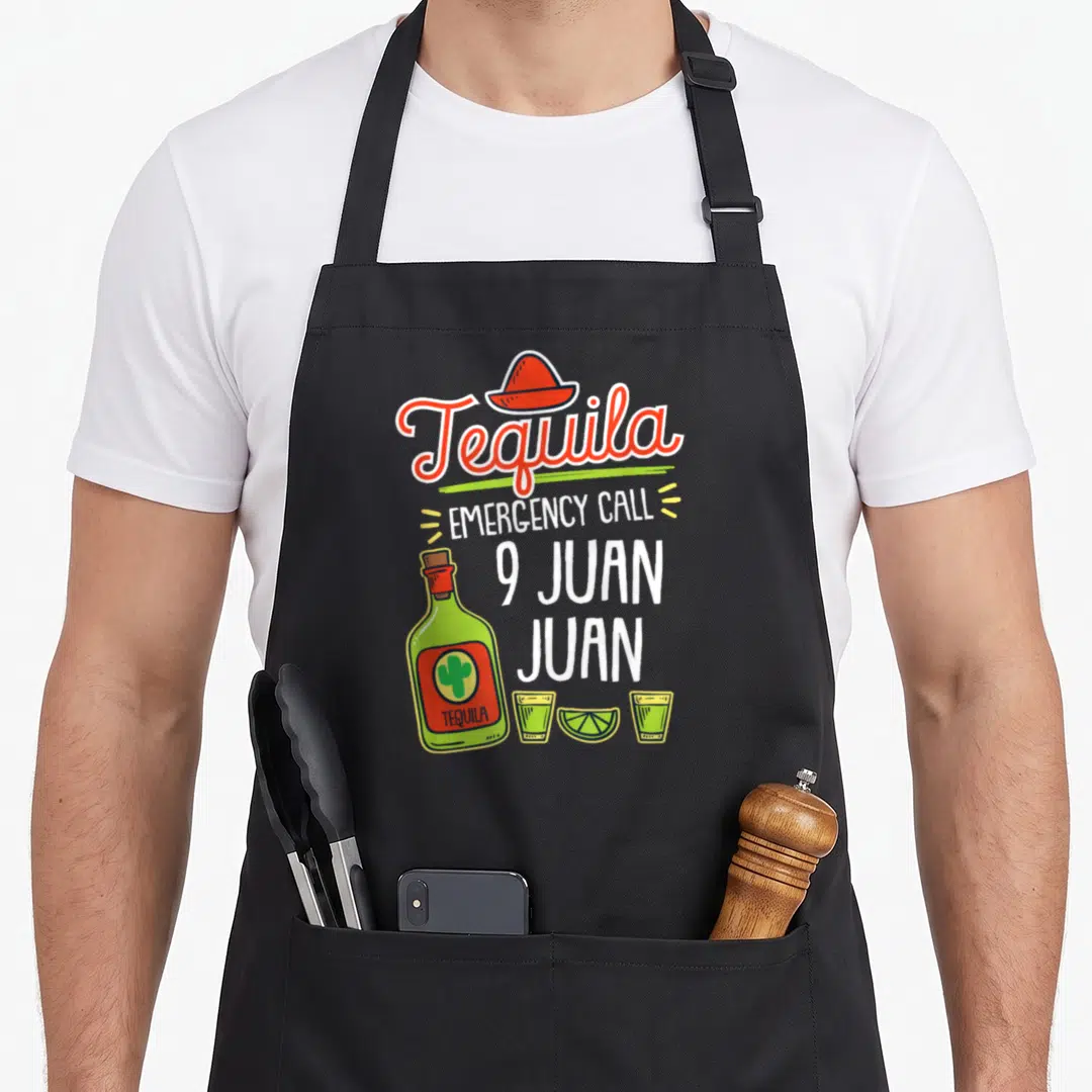 Tequila shot apron - Cartoon tequila bottle with sombrero, two shot glasses, lime slice, and 9 Juan Juan text — shown on a black cotton canvas apron against a white background