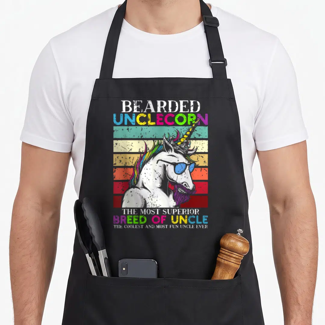 Bearded unicorn apron - Retro unicorn with purple beard and blue sunglasses in front of colored stripes with Bearded — shown on a black cotton canvas apron against a white background