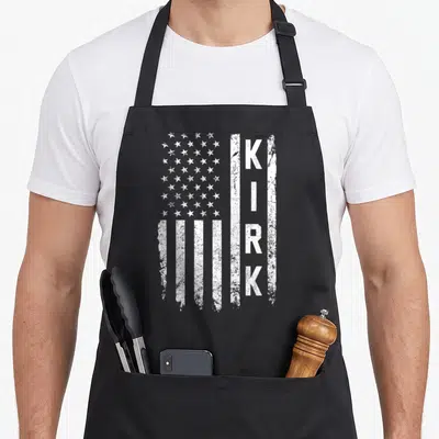 Kirk us aprons - Distressed white USA flag with vertical KIRK lettering on right side — shown on a black cotton canvas apron against a white background