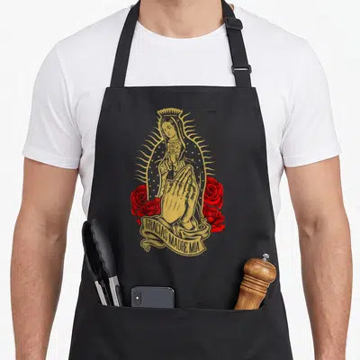 Virgen guadalupe mountains apron - Golden Virgin Mary and praying hands with red roses and Gracias Madre Mia ribbon text — shown on a black cotton canvas apron against a white background
