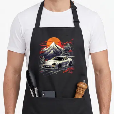Legend car apron - White JDM coupe with orange sun, grey wave, red clouds, and snow-capped mountain in retro style — shown on a black cotton canvas apron against a white background