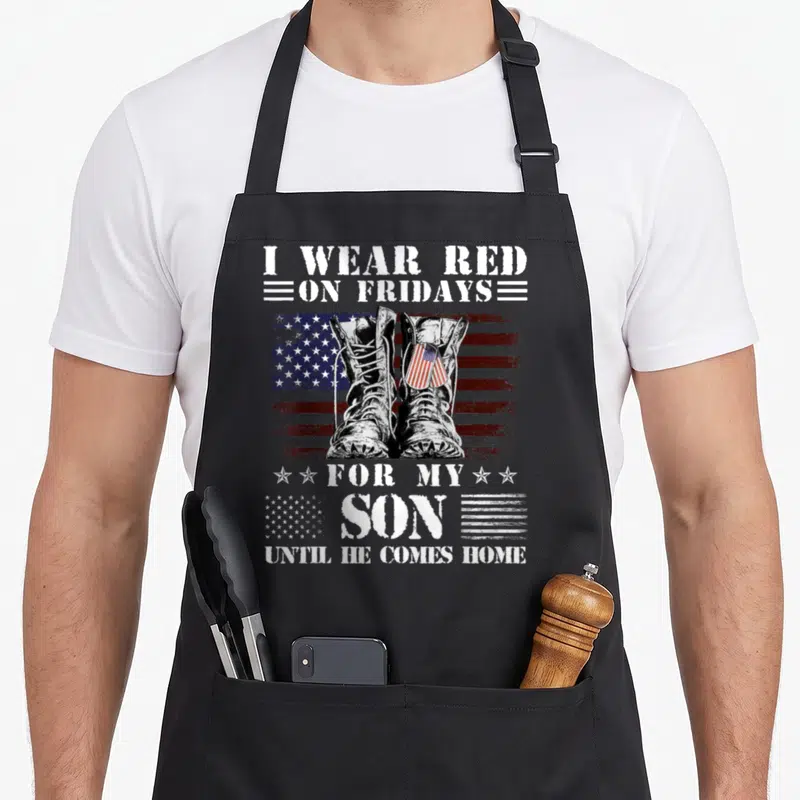 Friday novelty apron - Combat boots on distressed flag with text I WEAR RED ON FRIDAYS FOR MY SON — shown on a black cotton canvas apron against a white background