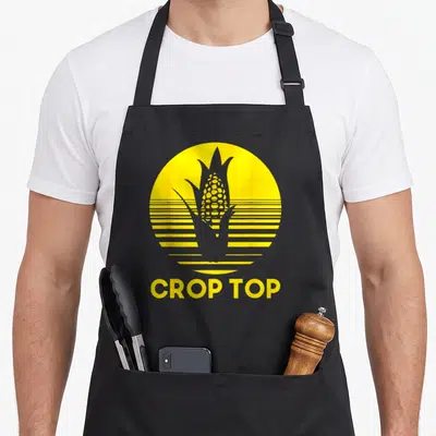 Corn farmer apron - Yellow circle with corn silhouette and CROP TOP text below — shown on a black cotton canvas apron against a white background