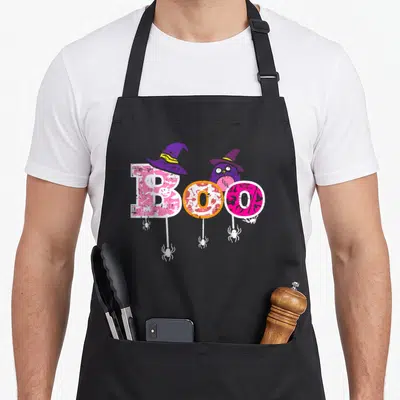 Boo owl apron - BOO text with witch hat owl, hanging spiders, and pink purple orange patterns — shown on a black cotton canvas apron against a white background