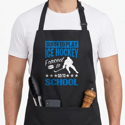 Play forced school apron - Blue and white distressed hockey player silhouette with BORN TO PLAY ICE HOCKEY text — shown on a black cotton canvas apron against a white background