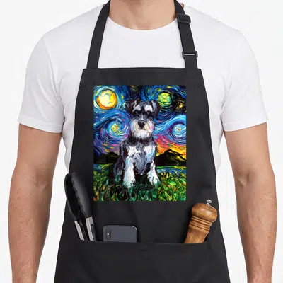 Night schnauzer apron - Impressionist dog sitting on green grass under swirling blue and yellow starry night sky — shown on a black cotton canvas apron against a white background