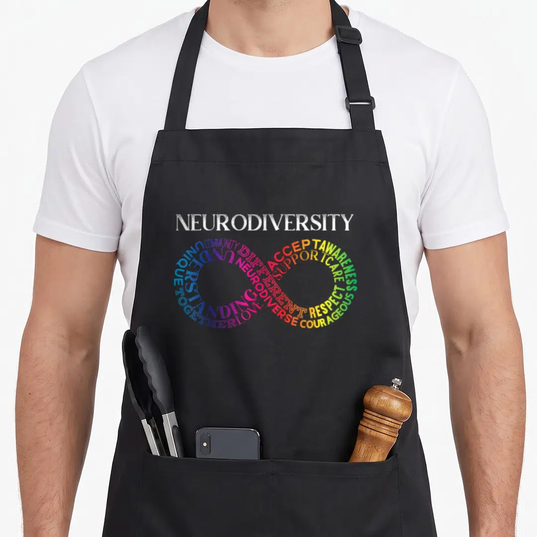 Neurodivergent rainbow apron - Infinity symbol formed by words ACCEPT, LOVE, RESPECT in rainbow colors — shown on a black cotton canvas apron against a white background