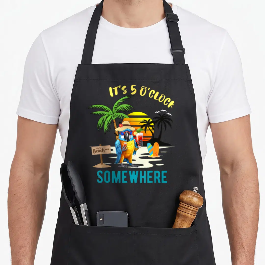 Oclock parrot lover apron - Cartoon parrot holding drinks between palm trees and surfboards with IT'S 5 O'CLOCK — shown on a black cotton canvas apron against a white background