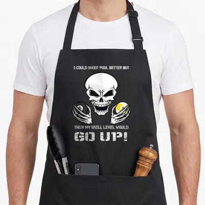 Could billiards apron - Cartoon skull holding black 8-ball and yellow-striped 9-ball with humorous pool text — shown on a black cotton canvas apron against a white background