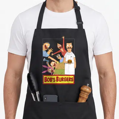 Family bobs burger apron - Group of five cartoon characters above yellow sign with red BOB'S BURGERS text — shown on a black cotton canvas apron against a white background