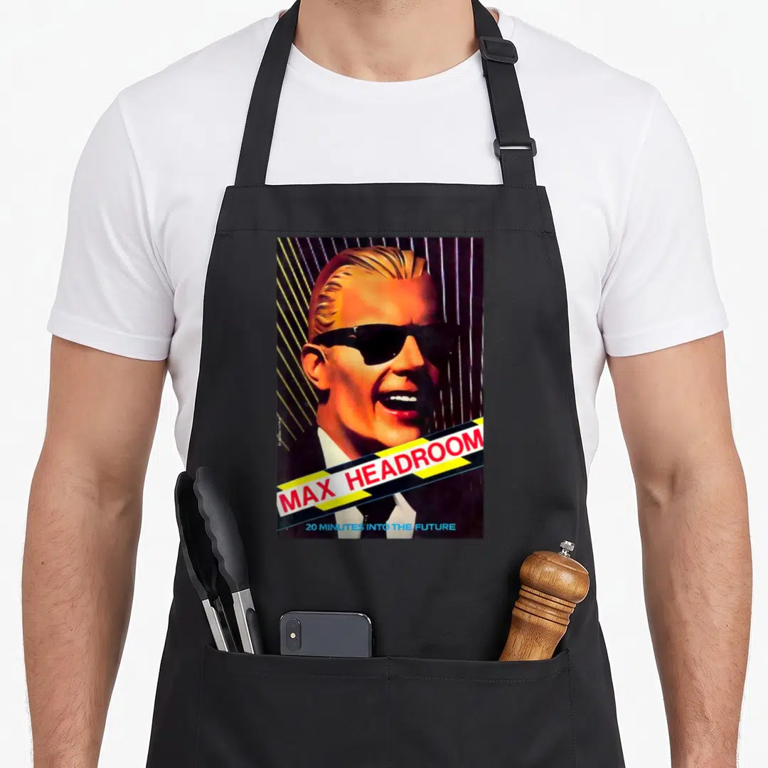 Actor beautiful apron - Man portrait with diagonal yellow black tape reading MAX HEADROOM and blue text below — shown on a black cotton canvas apron against a white background