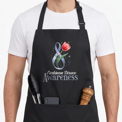 Support tulip apron - Red tulip intertwined with blue-grey ribbon and white stars above stacked text — shown on a black cotton canvas apron against a white background
