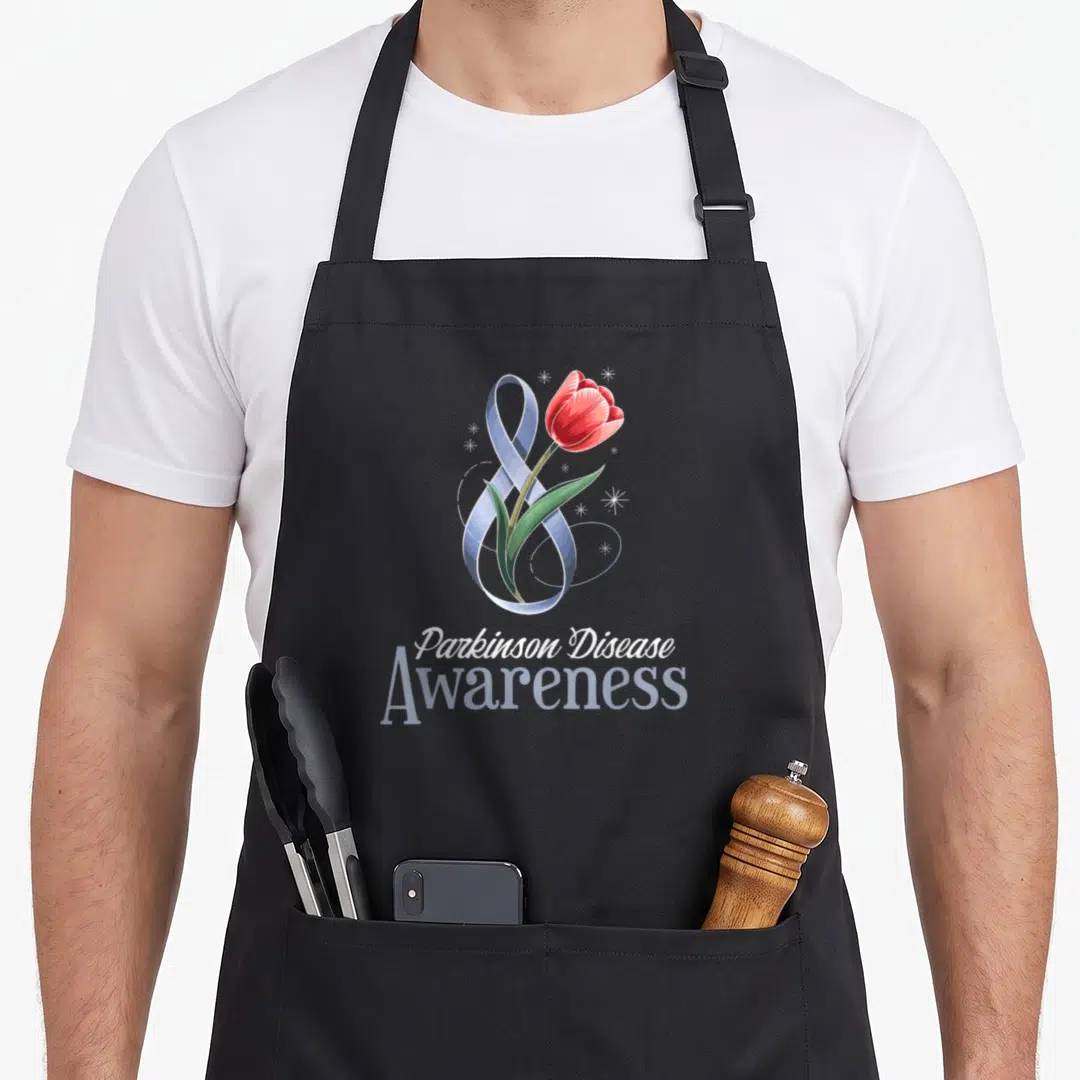 Support tulip apron - Red tulip intertwined with blue-grey ribbon and white stars above stacked text — shown on a black cotton canvas apron against a white background