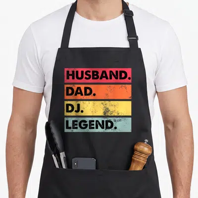 Legend husband apron - Four stacked colored rectangles with black text reading Husband Dad DJ Legend — shown on a black cotton canvas apron against a white background