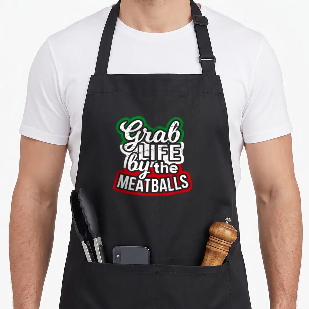 Funny pride italian aprons - Distressed Grab Life By The Meatballs text on Italian flag colors green white red — shown on a black cotton canvas apron against a white background
