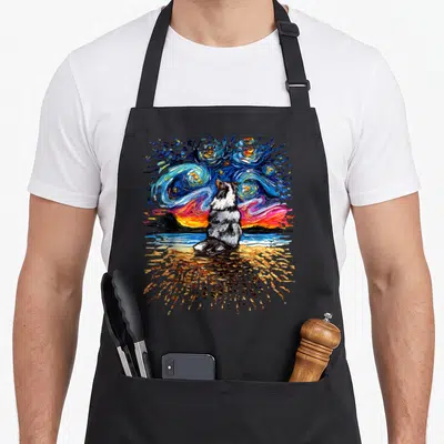 Shetland dog apron - Watercolor Merle Shetland Sheepdog sitting on a beach under a swirling blue and orange starry — shown on a black cotton canvas apron against a white background