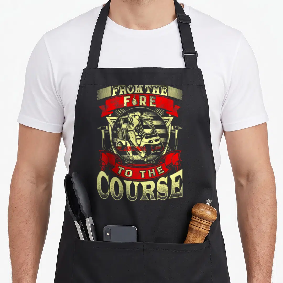Course firefighter cooking apron - Distressed red yellow From The Fire To The Course emblem with golf cart and axes — shown on a black cotton canvas apron against a white background