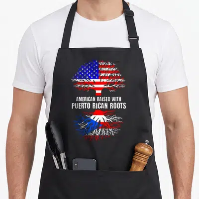 Rican american flag apron - Tree with American flag branches and Puerto Rican roots with text AMERICAN RAISED — shown on a black cotton canvas apron against a white background