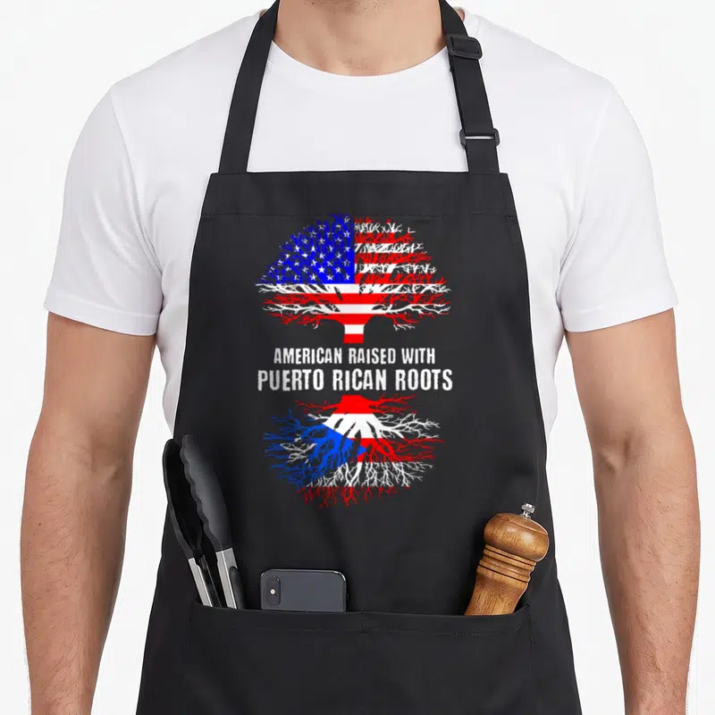 Rican american flag apron - Tree with American flag branches and Puerto Rican roots with text AMERICAN RAISED — shown on a black cotton canvas apron against a white background