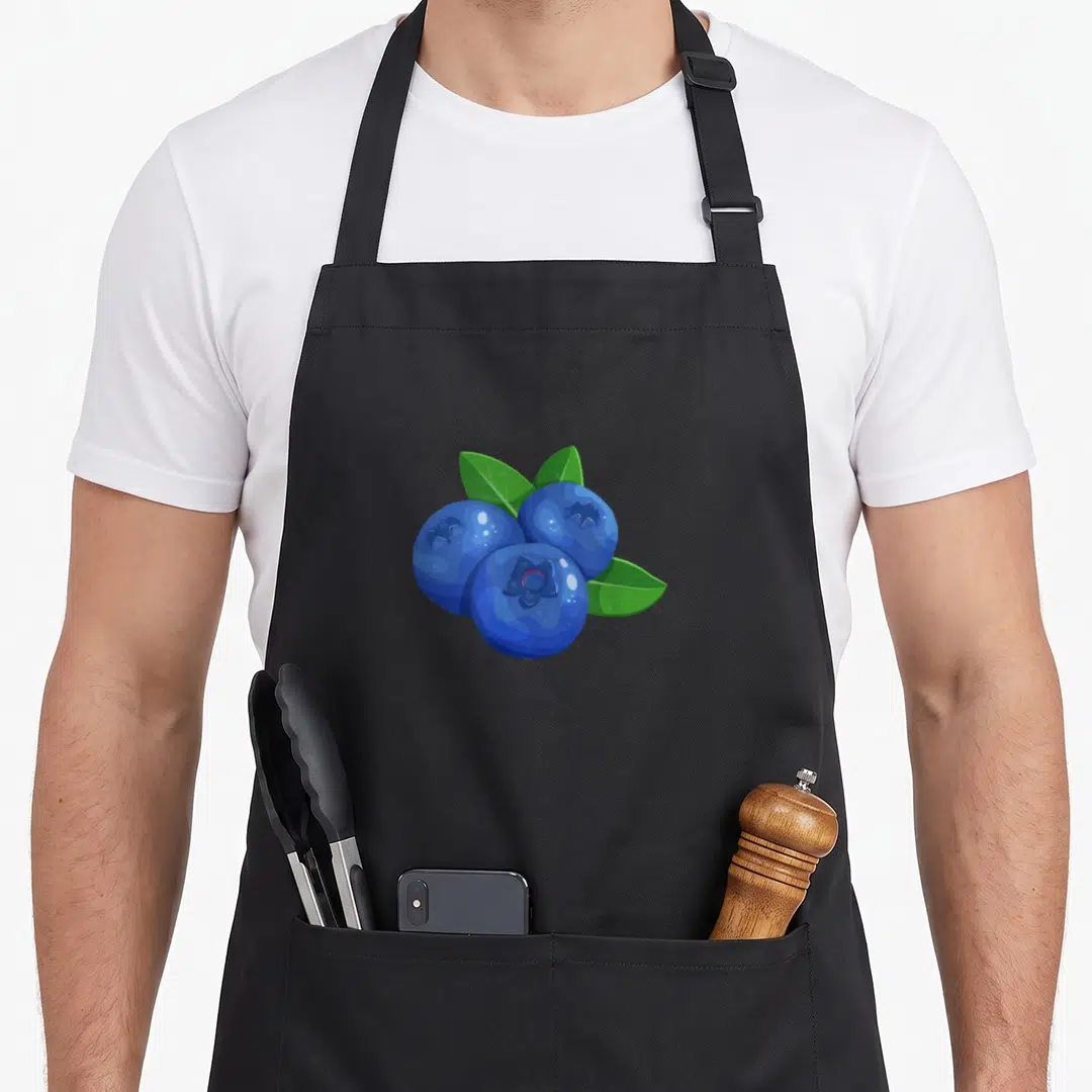Berry fruit apron - Three blue cartoon blueberries with three green leaves tucked behind them — shown on a black cotton canvas apron against a white background