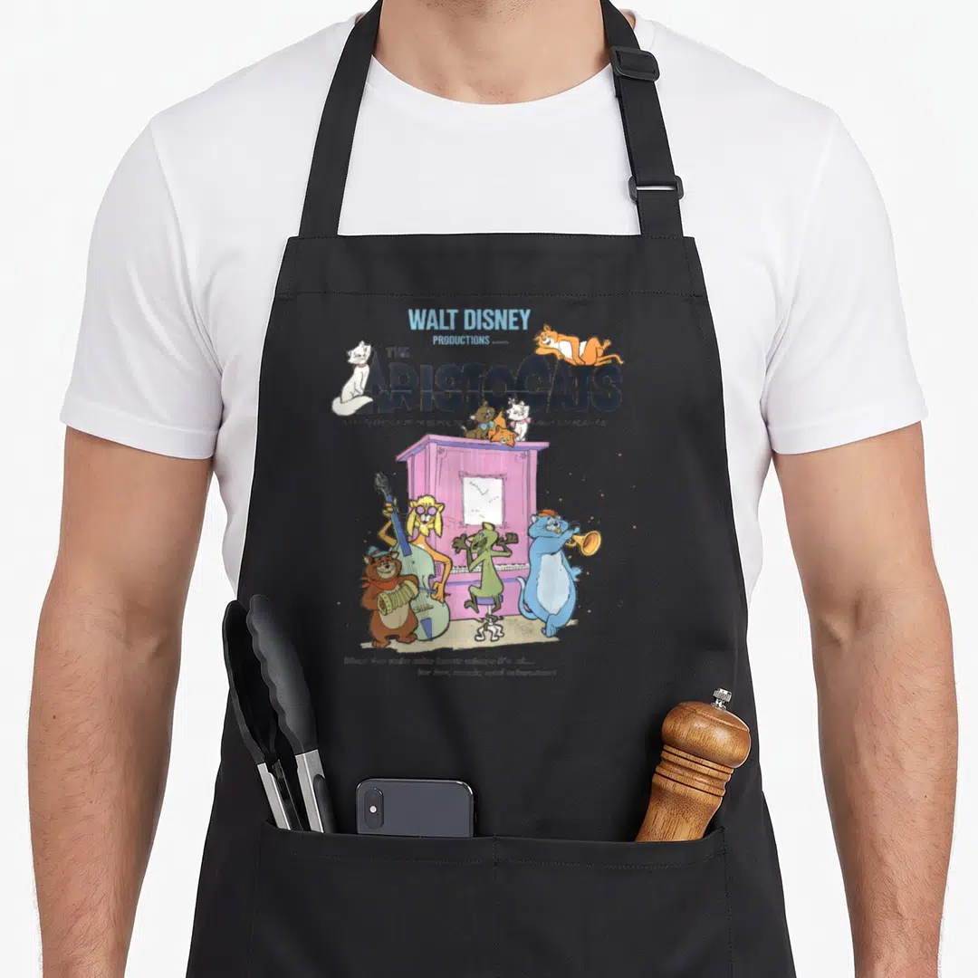 Aristocat piano apron - Vintage Aristocats title with cats playing instruments around a purple piano — shown on a black cotton canvas apron against a white background