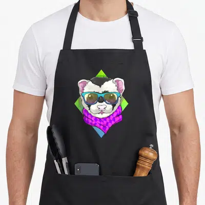 Hipster face apron - Cartoon ferret wearing blue sunglasses and purple scarf over green and blue diamond background — shown on a black cotton canvas apron against a white background