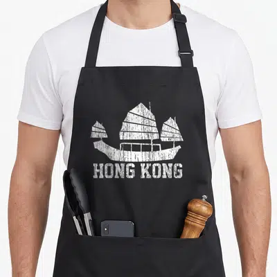 Funny hong kong apron - Distressed white junk boat silhouette above HONG KONG text — shown on a black cotton canvas apron against a white background