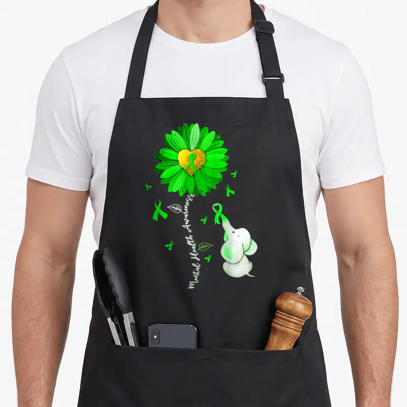 Health sunflower apron - Green watercolor flower with Mental Health Awareness text and elephant holding ribbon — shown on a black cotton canvas apron against a white background