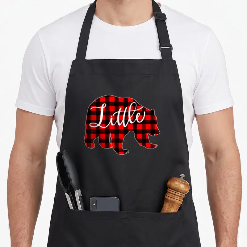 Bear family buffalo plaid christmas apron - Red and black plaid bear silhouette with Little in white script — shown on a black cotton canvas apron against a white background