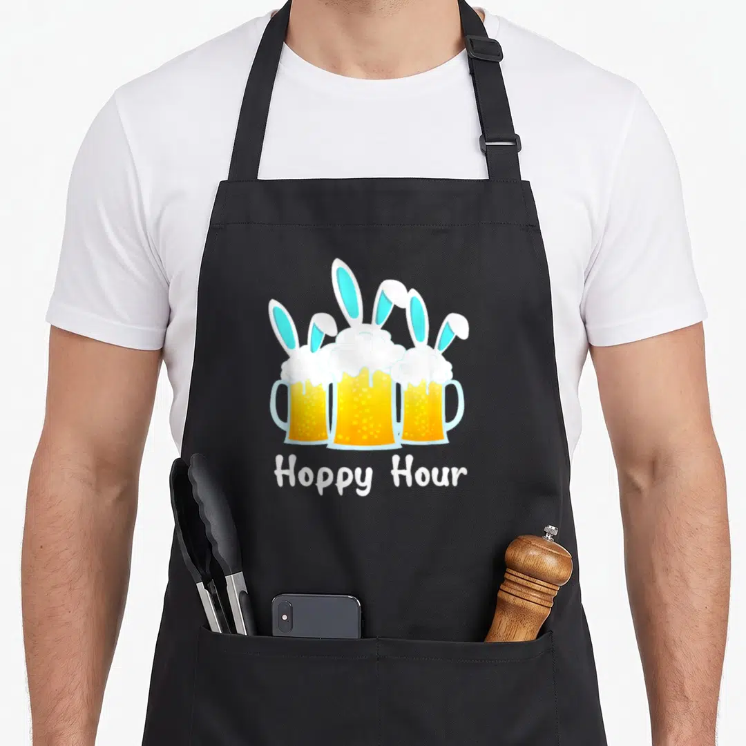 Punny easter bunny aprons - Three yellow beer mugs with rabbit ears and Hoppy Hour text in cartoon style — shown on a black cotton canvas apron against a white background