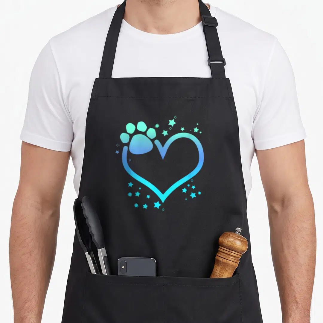 Blue paw print apron - Gradient heart outline with paw print and scattered stars in blue and cyan — shown on a black cotton canvas apron against a white background