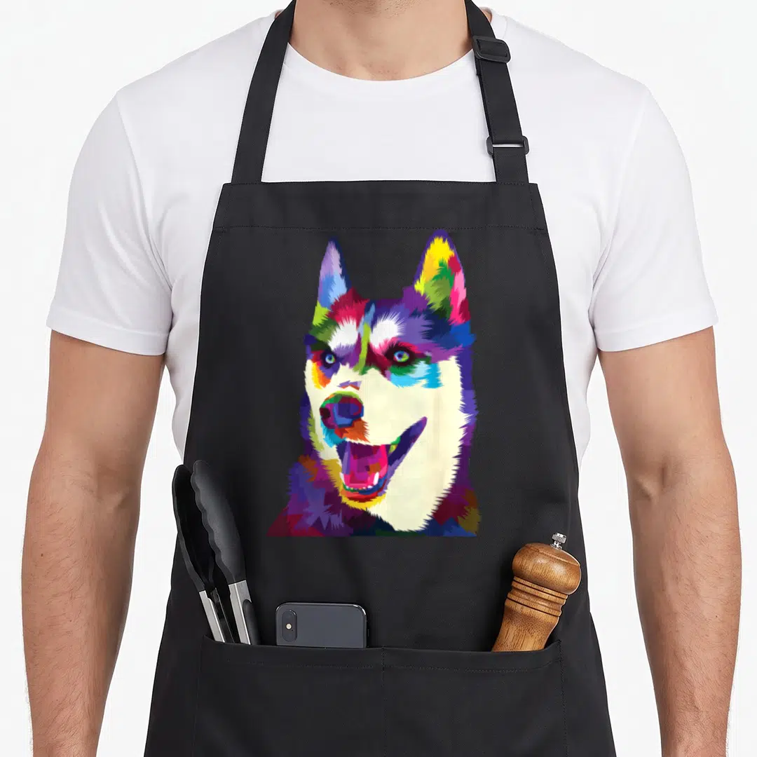 Colorful husky apron - Pixel art husky head portrait in blue, red, yellow, green, and purple colors — shown on a black cotton canvas apron against a white background