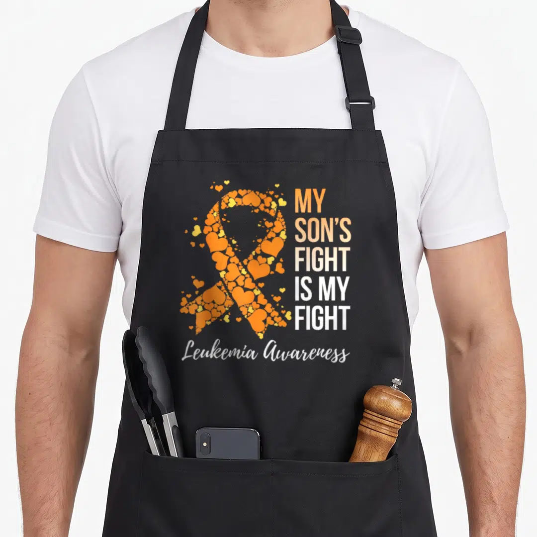 Son doctor dad apron - Orange hearts forming a ribbon next to My Son's Fight Is My Fight text — shown on a black cotton canvas apron against a white background