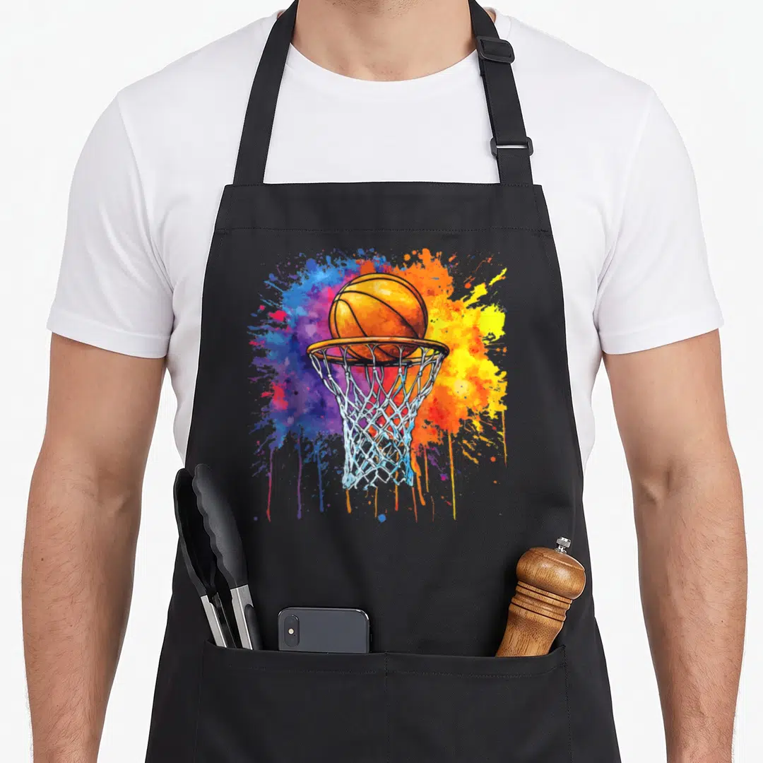 Drip colorful aprons - Orange basketball in a hoop with blue yellow and purple watercolor paint splashes — shown on a black cotton canvas apron against a white background