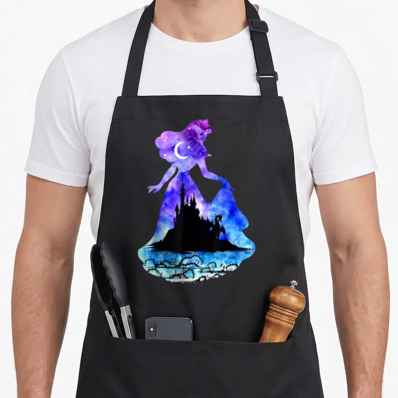 Castle beauty apron - Galaxy woman silhouette with black castle, dragon, moon, and thorns in purple and blue watercolor — shown on a black cotton canvas apron against a white background