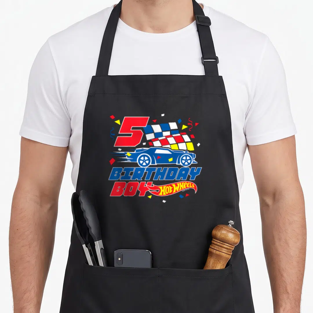 5th wheel apron - Red number 5, blue race car, checkered flag, and birthday boy text with confetti — shown on a black cotton canvas apron against a white background
