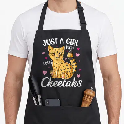 Vintage cheetah apron - Cartoon yellow cheetah with pink hearts and white text Just A Girl Who Loves Cheetahs — shown on a black cotton canvas apron against a white background