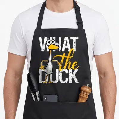 Humorous cotton duck aprons - Cartoon duck overlapping white and yellow text reading What the Duck — shown on a black cotton canvas apron against a white background