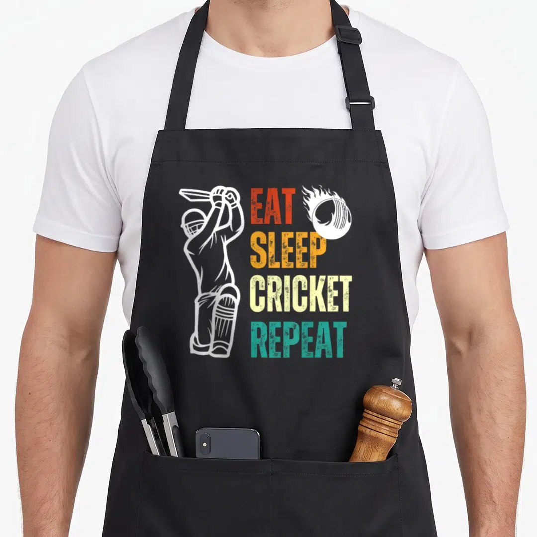 Eat cricket apron - White cricketer outline next to stacked EAT SLEEP CRICKET REPEAT text in red, orange, yellow — shown on a black cotton canvas apron against a white background