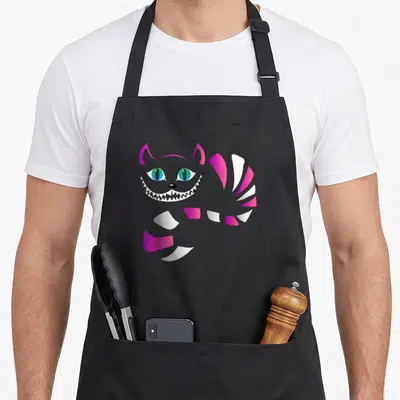 Faced cat apron - Grey cartoon cat head with pink ears and striped tail curving right — shown on a black cotton canvas apron against a white background