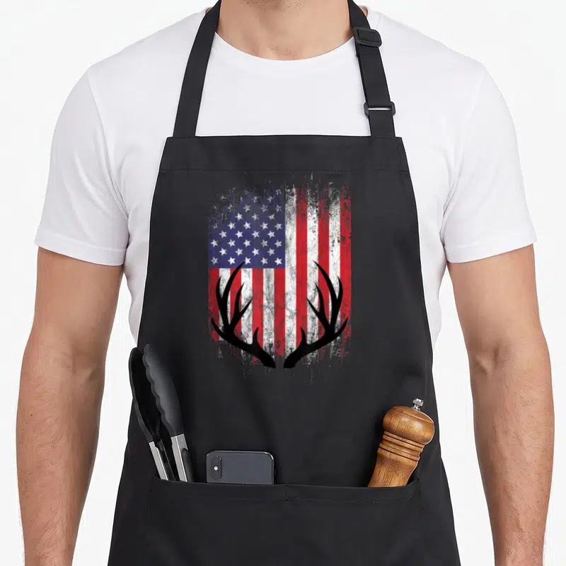 Deer american flag apron - Black deer antlers silhouette overlaid on a distressed red white and blue American flag — shown on a black cotton canvas apron against a white background