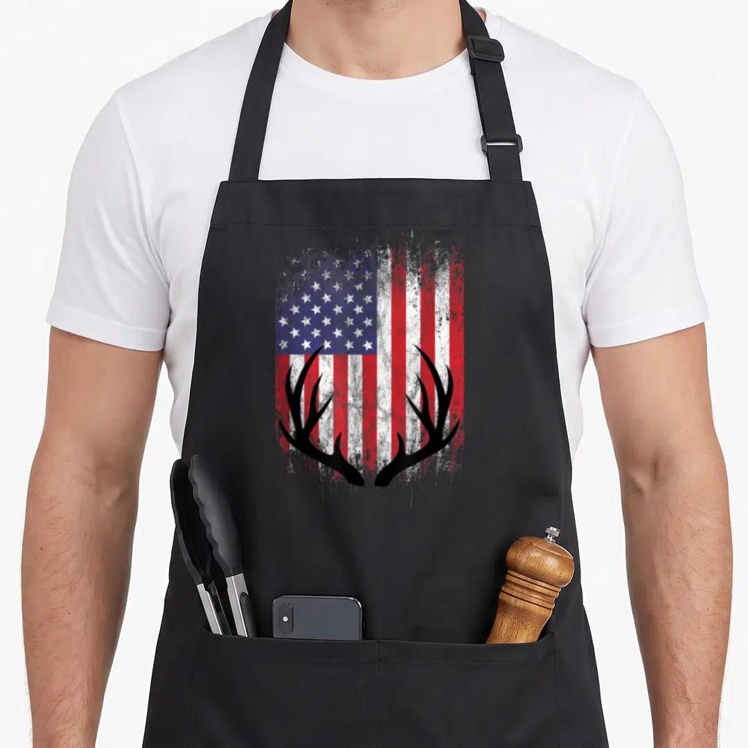 Deer american flag apron - Black deer antlers silhouette overlaid on a distressed red white and blue American flag — shown on a black cotton canvas apron against a white background