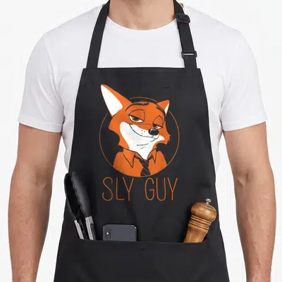 Wilde fox aprons - Orange cartoon fox face in circle with SLY GUY text below — shown on a black cotton canvas apron against a white background