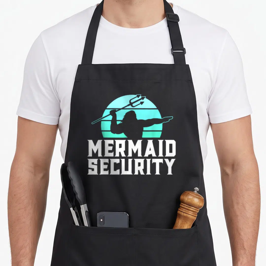 Swimmer mermaid apron - Merman silhouette holding trident over teal gradient sun with MERMAID SECURITY text — shown on a black cotton canvas apron against a white background