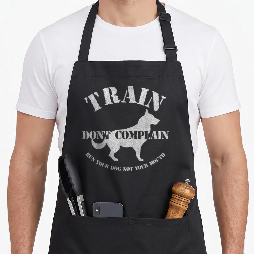 Trainer dog training apron - Distressed white dog profile silhouette with arched TRAIN and DONT COMPLAIN text — shown on a black cotton canvas apron against a white background