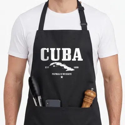 Cuba est pride apron - Distressed white CUBA text, map outline, EST 1898, PATRIA O MUERTE, and star on black background — shown on a black cotton canvas apron against a white background