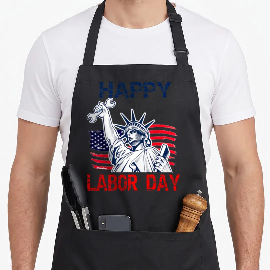 Labor liberty apron - Distressed Statue of Liberty holding wrench with Happy Labor Day text in red and blue — shown on a black cotton canvas apron against a white background