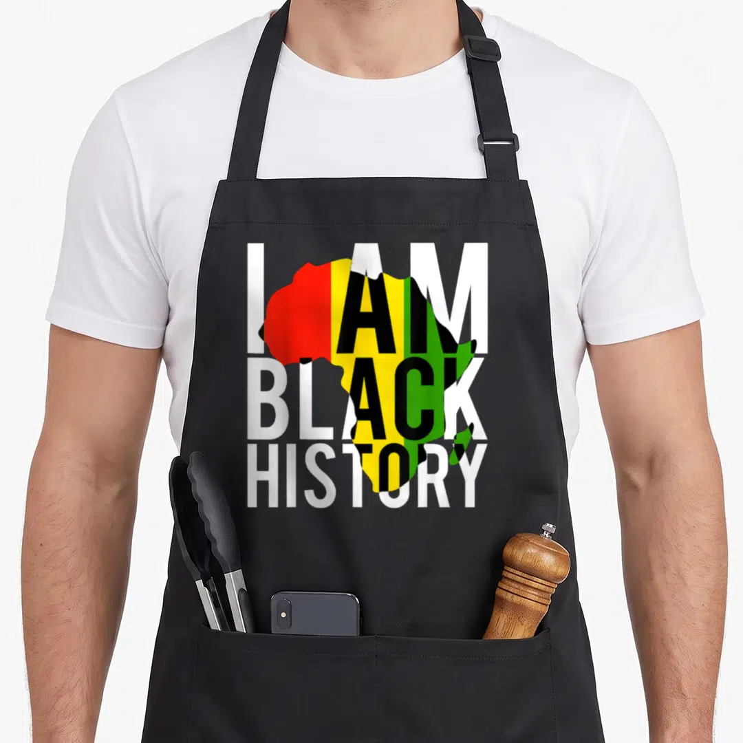 History pride apron - Stacked I AM BLACK HISTORY text over red yellow green map of Africa — shown on a black cotton canvas apron against a white background