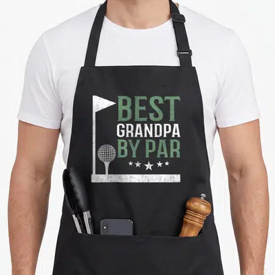 Grandpa par father day apron - Distressed green and white BEST GRANDPA BY PAR text with golf flag border, ball on tee — shown on a black cotton canvas apron against a white background