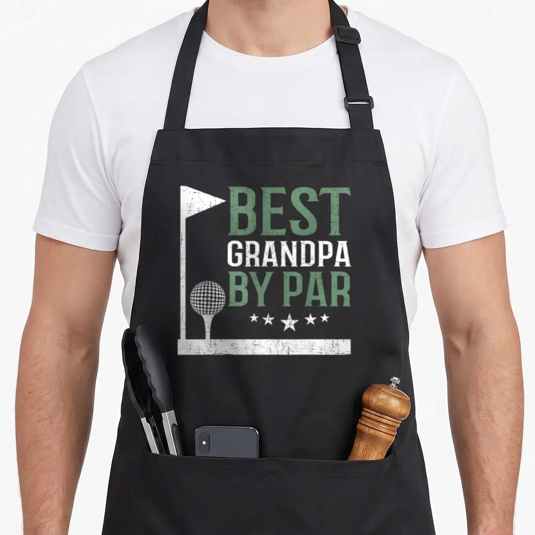 Grandpa par father day apron - Distressed green and white BEST GRANDPA BY PAR text with golf flag border, ball on tee — shown on a black cotton canvas apron against a white background